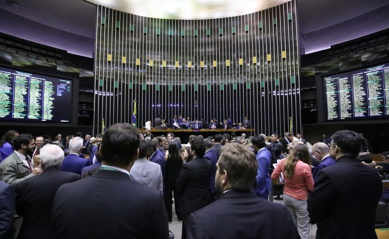 Plenário da Câmara dos Deputados durante sessão de votação, com parlamentares reunidos e painéis eletrônicos exibindo resultados.